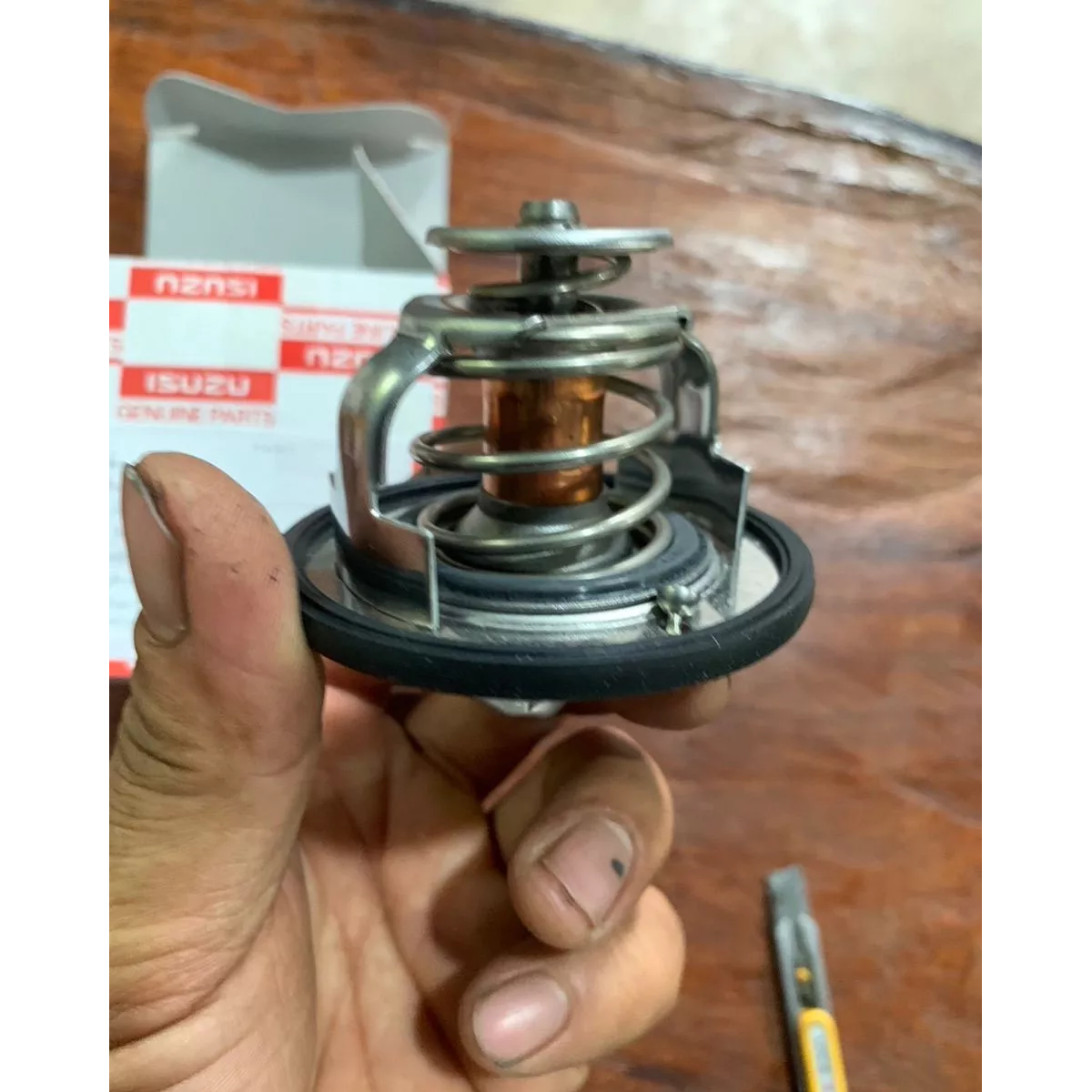 Close-up side view of Isuzu thermostat with spring assembly and black sealing ring